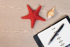 Blank notebook and pen with starfish on office table