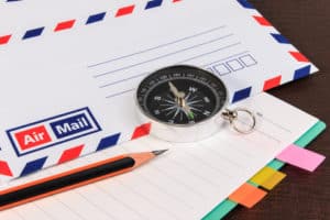 Notebook, envelopes airmail, notebook, compass and pencil on wood floor. A close up view.